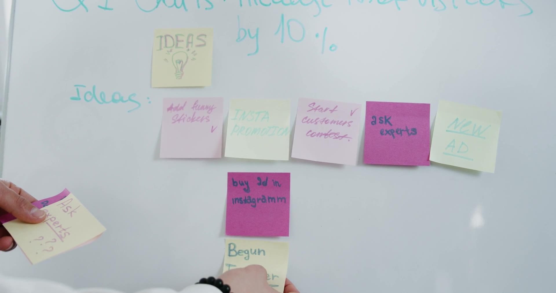 Hands arranging colorful sticky notes on a whiteboard during a planning session