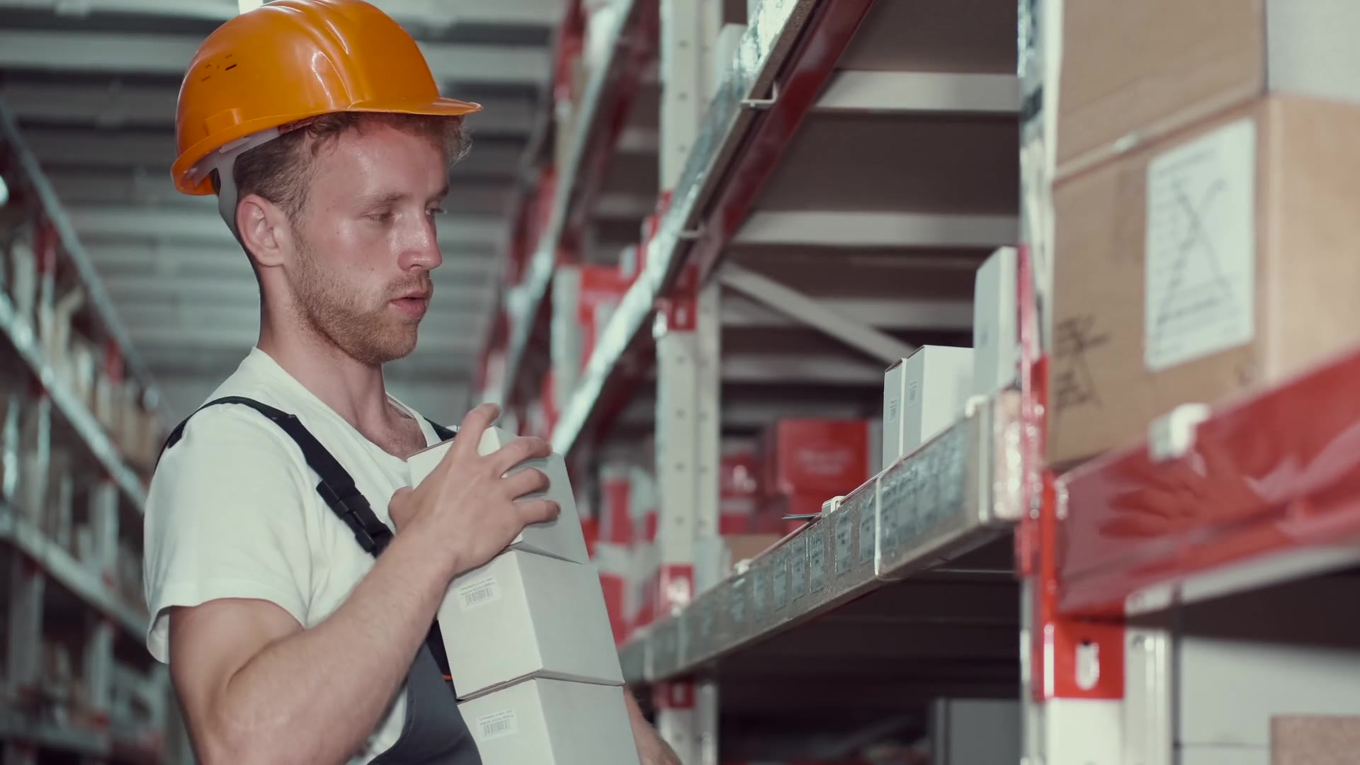 Warehouse worker in a hard hat placing boxes on shelves